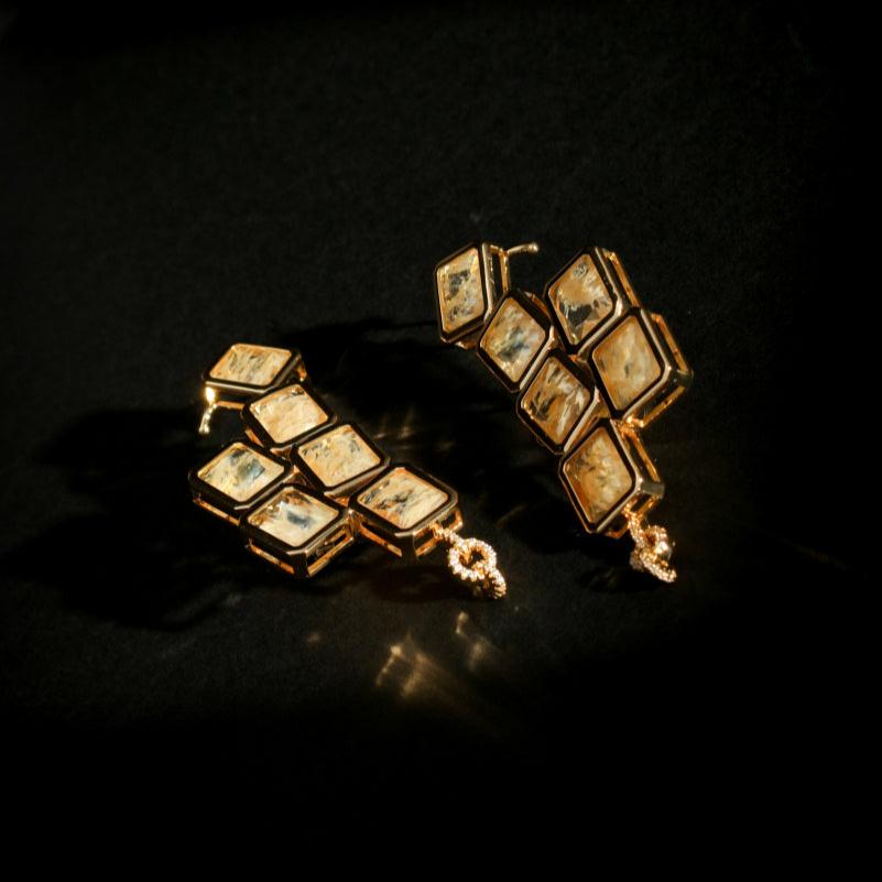 Auric Cuff Stud flat lay with gold crystals on black background