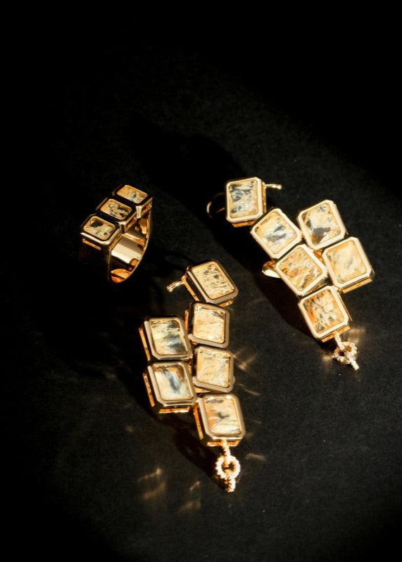 Auric Cuff Stud grouped with other gold jewelry on black surface