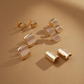 Flatlay of Golden Halo Earrings on a sand-colored surface with scattered crystals
