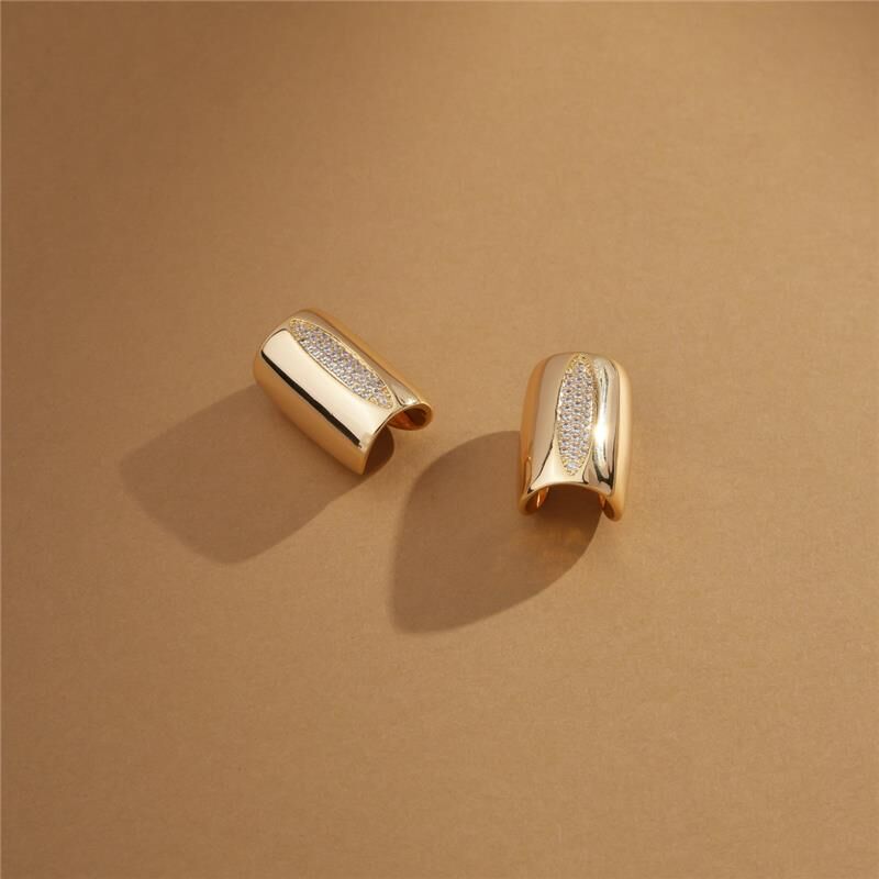 Adjustable white gold earrings with zirconia in flatlay on neutral background