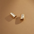 Adjustable white gold earrings with zirconia in flatlay on neutral background