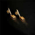 Vega Drop Earrings flat lay gold plated crystal earrings on black background
