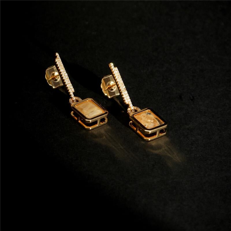 Vega Drop Earrings flat lay gold plated crystal earrings on black background