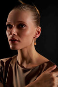 Close up of model wearing Vega Drop Earrings elegant gold plated statement piece